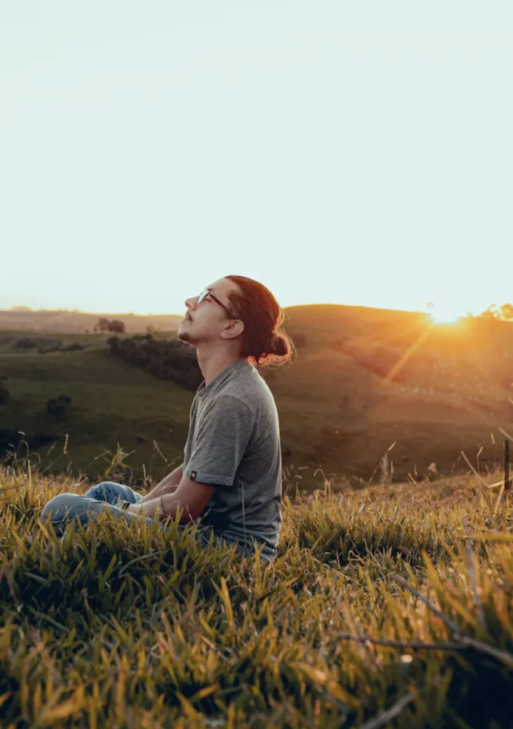 man sitting in the sunlit field of grass